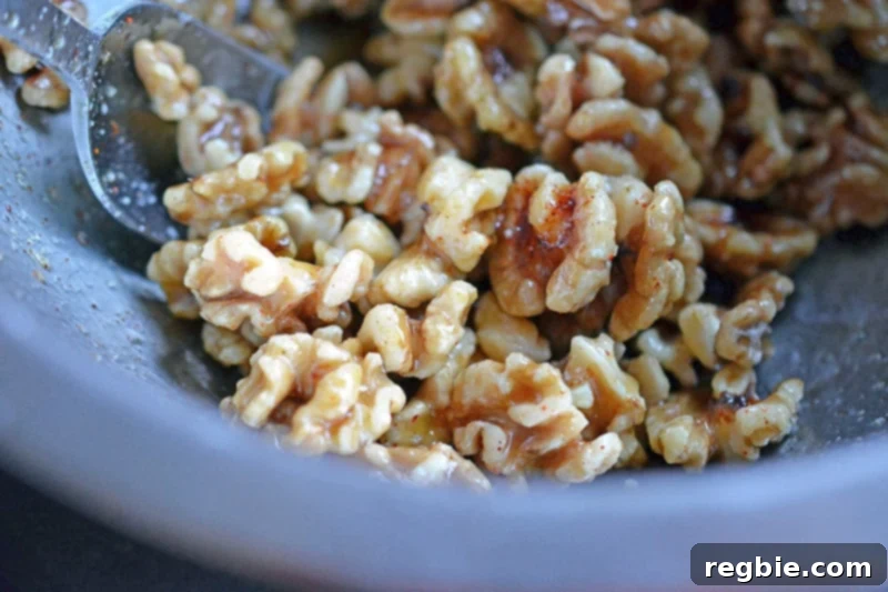 Tossing maple spiced walnuts in a bowl, ensuring each piece is fully coated for our gluten-free Paleo Walnut Shrimp.