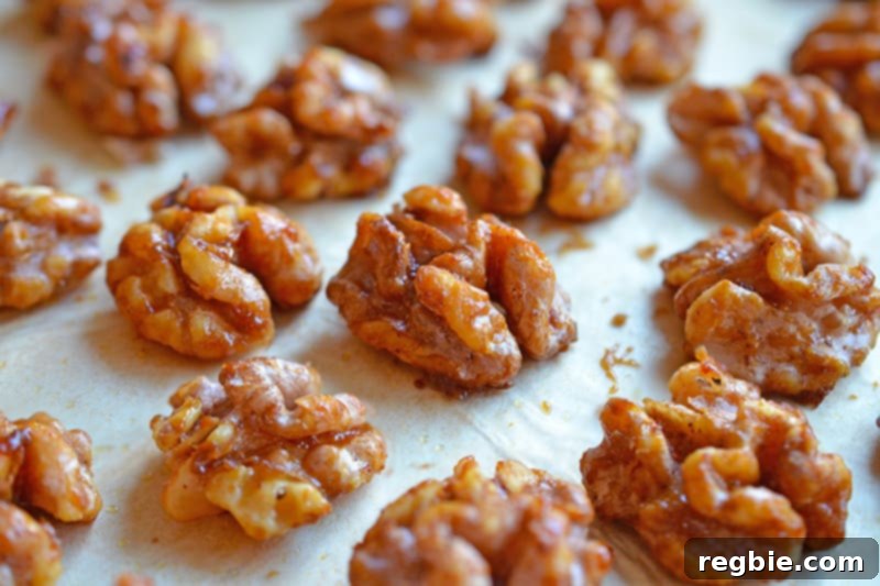 Close up shot of sweetened gluten-free walnuts baking on a piece of parchment paper, showing a golden brown finish.
