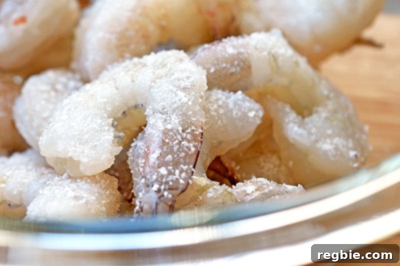 Close up shot of raw shrimp generously seasoned with Diamond Crystal kosher salt.