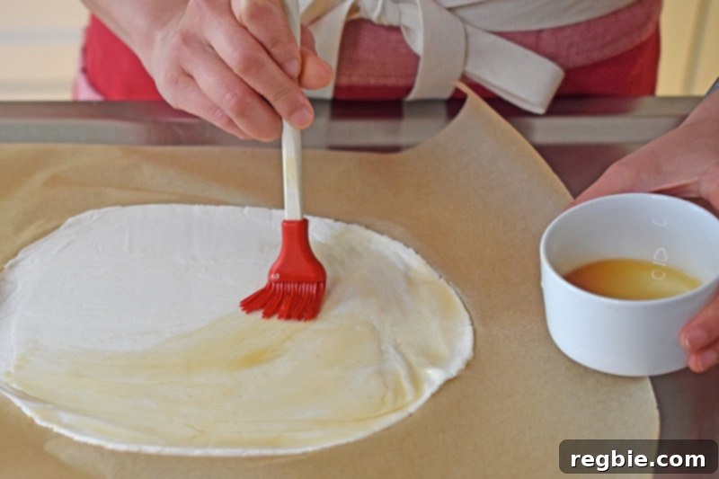 Brushing sesame oil on a flattened piece of cassava flour dough to make vegan and paleo scallion pancakes
