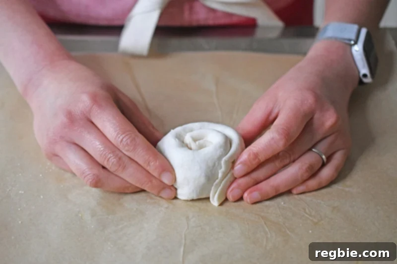 Someone holding a Paleo Scallion Pancake dough that has been formed to look like a cinnamon roll.