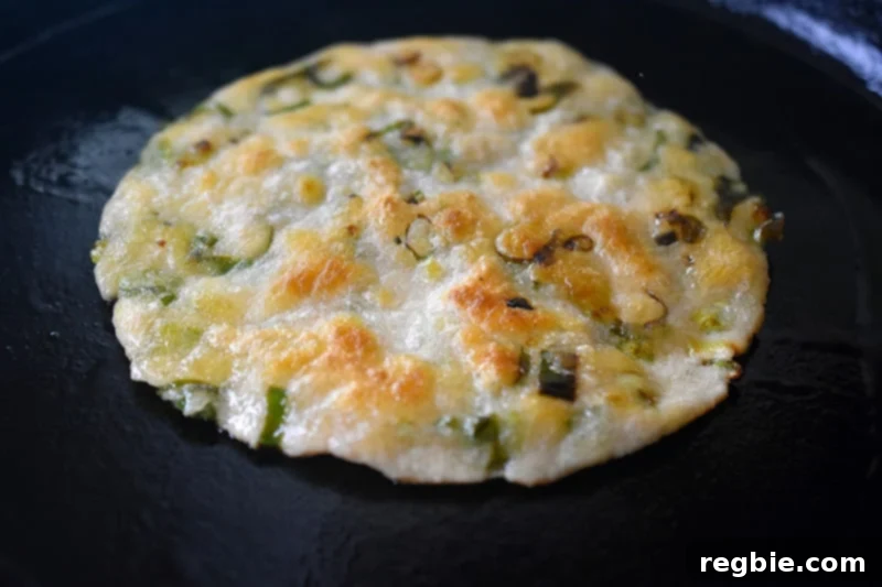 A closeup shot of a crispy Paleo Scallion Pancake in a cast iron skillet.