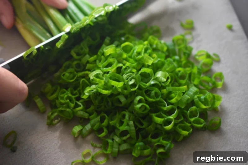 A closeup shot of someone thinly slicing scallions to make Paleo and gluten-free Scallion Pancakes 