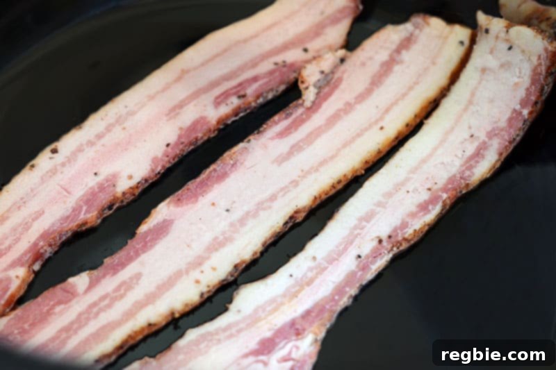 Three slices of raw bacon laid flat on the bottom of a slow cooker, creating a base for the pork roast.