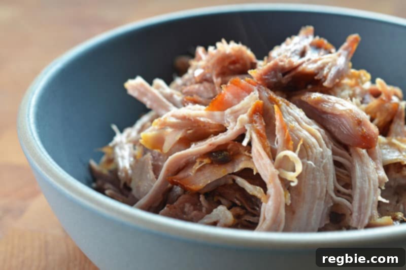 A close-up of perfectly shredded Slow Cooker Kalua Pig served in a rustic blue bowl, garnished and ready to eat.