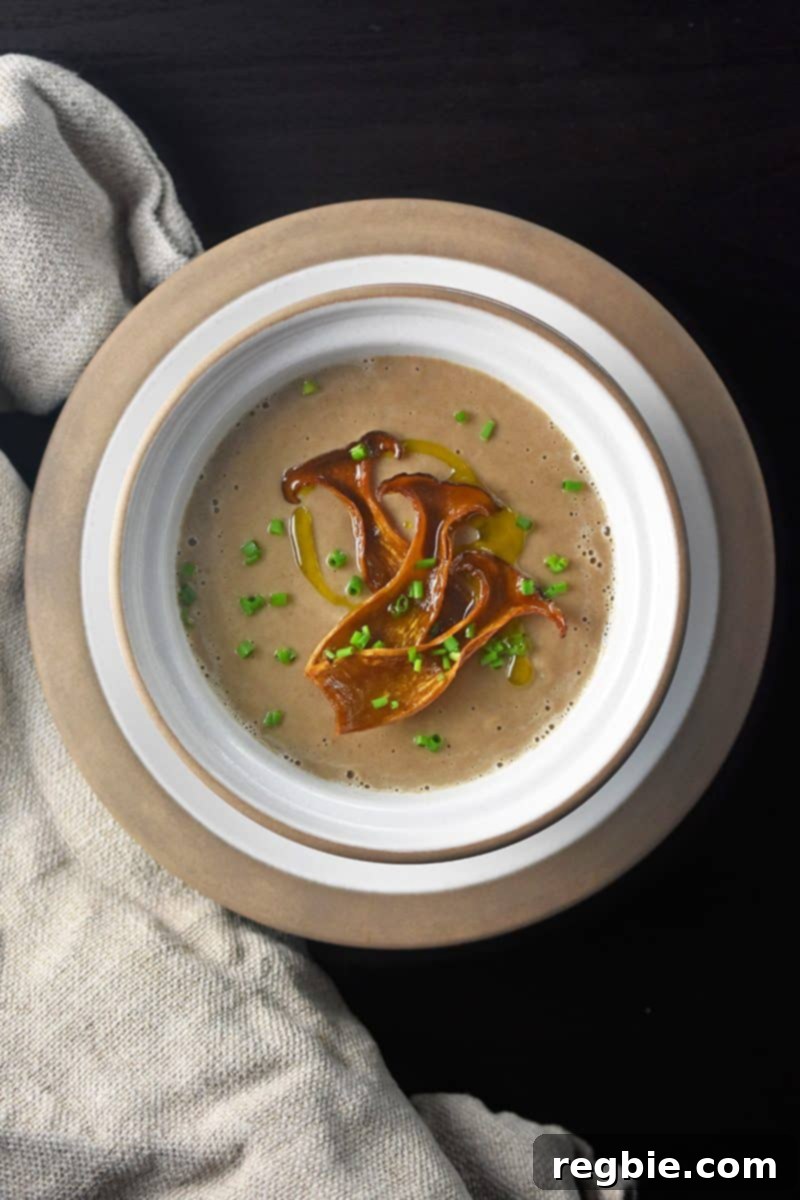 A bowl of Instant pot cream of mushroom soup topped with mushrooms and fresh herbs.