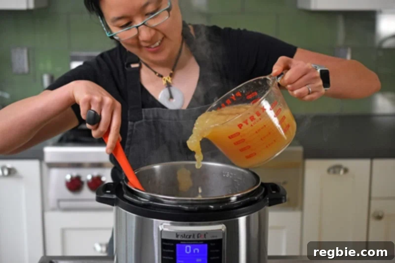 Someone pouring in bone broth into the Instant Pot for Instant Pot cream of mushroom soup.