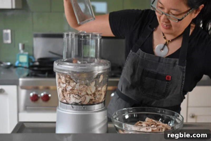 Someone putting mushrooms into a food processor for paleo Instant pot mushroom soup.