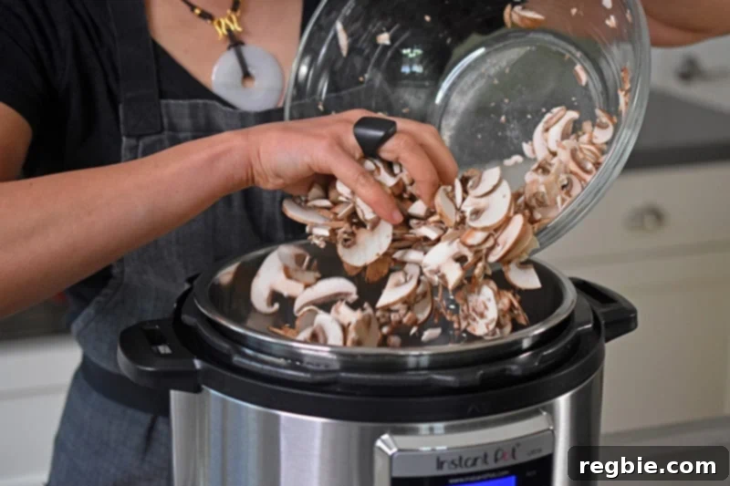 Someone dumping a bowl of chopped mushrooms into an Instant Pot.