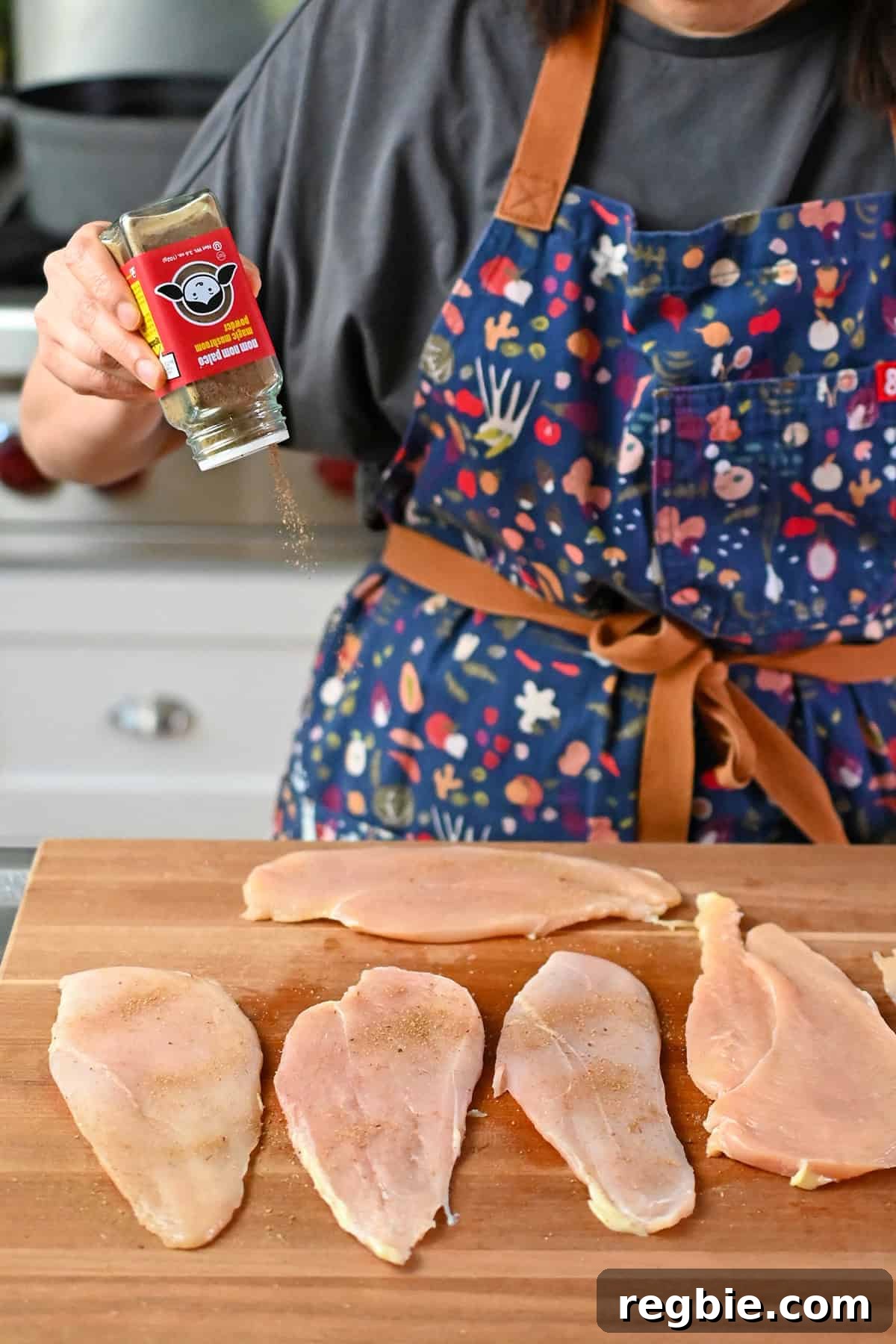 How I Cook Juicy, Tender Chicken Breasts Every Time 7 Sprinkling seasoning onto thinly pounded raw chicken breast cutlets on a wooden cutting board.